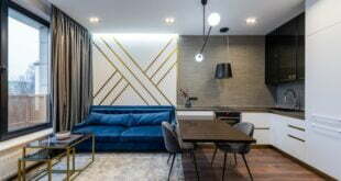 Nowoczesny salon z kuchnią, minimalistyczny wystrój, wygodna sofa i nowoczesne oświetlenie.
